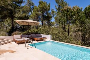 einen Pool mit einem Sonnenschirm und Stühlen sowie einem Tisch und einem Sonnenschirm in der Unterkunft Villa Can Secorrat in Can Furnet