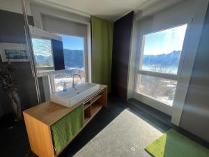 a bathroom with a sink and two windows at Belle Maison au cœur des alpes in Leysin