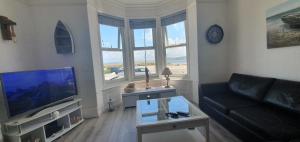a living room with a couch and a flat screen tv at Stunning Beachfront Apartment Sleeps 4 in Rhos-on-Sea