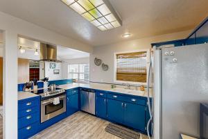 a blue and white kitchen with blue cabinets and a refrigerator at Happy Clam in Waldport +22 photos