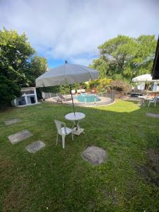 a table and chair with an umbrella in the grass at Hotel Capri in Villa Gesell