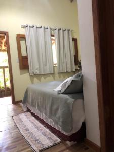 a bedroom with a bed and a window with curtains at CASA MEDNA in Trancoso