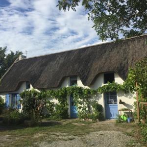 a white cottage with a thatched roof at Linotte Chaumière des Marionnettes in La Chapelle-des-Marais