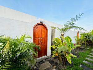 a wooden door on a white building with plants at Brahmastra Bali villa in Kubupenlokan