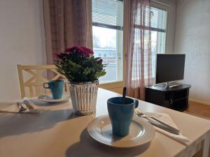 a table with two cups and a vase of flowers on it at Apia Super Stay, Sauna, 5pers in Valkeakoski