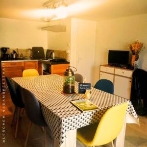 a dining room table with chairs and a kitchen at Les Chemins d'Ambre et Thaïs in La Regrippière +28 photos