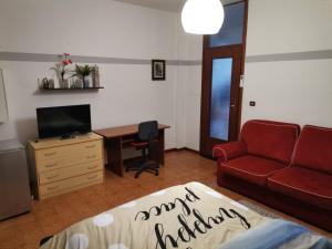 a living room with a red couch and a desk at Ampia camera con balcone privato in Pordenone