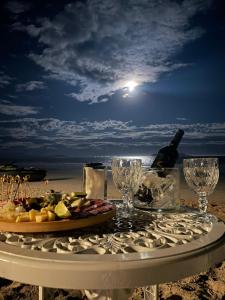 a table with a plate of food and wine glasses on the beach at Santo Gole Ilha Do Mel in Paranaguá