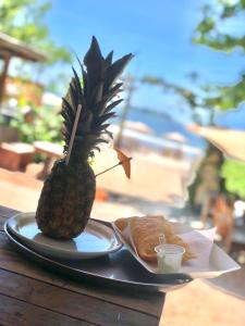 a pineapple sitting on top of a plate with a sandwich at Santo Gole Ilha Do Mel in Paranaguá