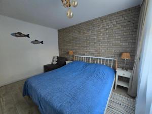 a bedroom with a blue bed and a brick wall at TROPIC-APARTAMENTY in Hel