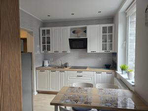 a kitchen with white cabinets and a table with chairs at TROPIC-APARTAMENTY in Hel