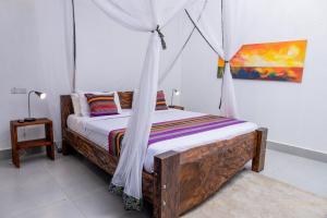 a bedroom with a wooden bed with a mosquito net at Kabalega Resort - Hoima in Hoima +35 photos