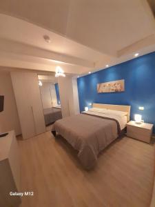 a bedroom with a large bed with a blue wall at RESIDENZA MENA marina CORRICELLA in Procida