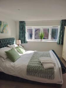 a bedroom with a large bed with green pillows at Beautiful dog friendly cosy village barn in Bridgwater