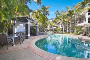 a pool at a resort with a table and chairs and palm trees at Blue Waters Apartments in Gold Coast