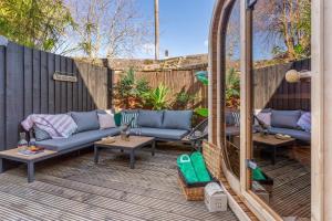 a patio with couches and tables and a fence at 5 min walk to beach with parking and private sauna in Falmouth