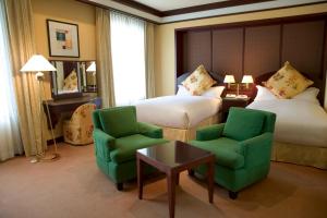 a hotel room with two beds and green chairs at Mito Plaza Hotel in Mito