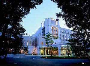 ein großes weißes Gebäude mit eingeschaltetem Licht in der Unterkunft Mito Plaza Hotel in Mito