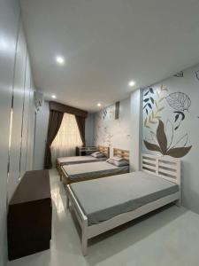 a bedroom with three beds and a wall with flowers at Ciudad Ezperanza near Davao Airport in Davao City