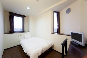 a bedroom with a bed and a tv and two windows at Athena Kaigetsu in Awaji