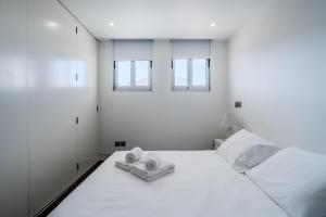 a white bedroom with two towels and two windows at H2O Apartment - Rooftop with pool in Santa Cruz in Santa Cruz +50 photos