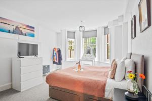 a white bedroom with a bed and a tv at Spacious one bed Apartment, contractor friendly, Sleeps 6, FREE Secure Parking, Near Beach in Bournemouth