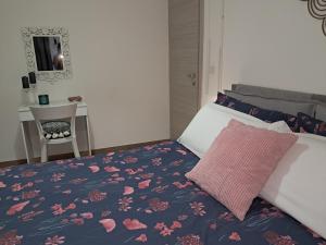 ein Schlafzimmer mit einem Bett mit einem rosa Kissen und einem Schreibtisch in der Unterkunft OLTREMARE holiday home in Catania