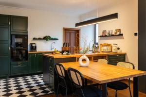 a kitchen with green cabinets and a wooden table with chairs at Tropical Wellness Suite I Sauna I Whirlpool I Hot Tub I TV I BBQ in Büdesheim