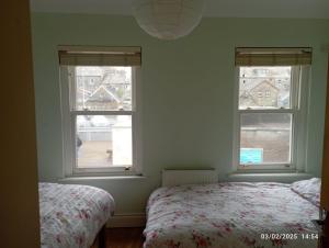 a bedroom with two beds and two windows at Town Centre House in Clonakilty