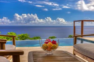 a glass bowl of fruit on a table with a view of the ocean at Villa Panorama Grand Anse in Petite Île