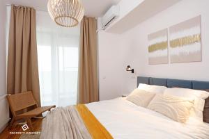 Un dormitorio con una cama blanca y una silla. en Fancy 2BR Pipera Apartment, en Voluntari