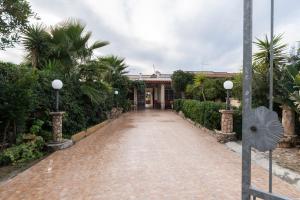 a brick road leading to a building with palm trees at Villa Angela in Sant'Isidoro