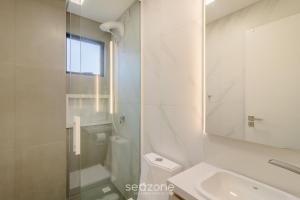 a white bathroom with a sink and a mirror at Apartamentos no Edifício Turquesa - Balneário Piçarras - RTS in Piçarras +33 photos