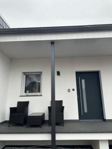 un groupe de chaises et une porte sur un bâtiment dans l'établissement NEUES Apartment in Löhne, 50qm mit Moderner Küche, Boxspringbett und vieles mehr, à Löhne