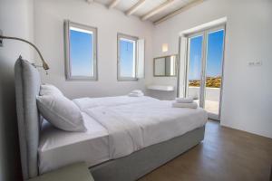 a white bedroom with a large bed and windows at Anarina Villas & Suites Elia Beach in Mýkonos City +137 photos