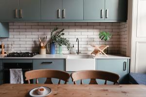 une cuisine avec des placards bleus et une table en bois dans l'établissement Beautiful central Edinburgh Apartment, à Édimbourg