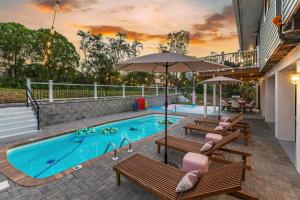 a swimming pool with benches and umbrellas next to at Casa Marco - Heated Pool, Game Room, Mini Golf in Marco Island