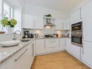 a white kitchen with white cabinets and a sink at 10 Cove View in Ilfracombe