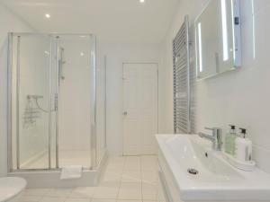 a white bathroom with a shower and a sink at 10 Cove View in Ilfracombe