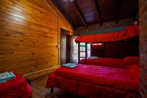 Dos camas en una habitación con paredes de madera. en Brisas del Sur, en El Bolsón