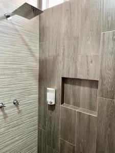 a bathroom with a shower with a wooden wall at Casa Madera - Departamento 2 in Tequila