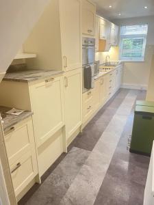 a kitchen with white cabinets and a tile floor at East Durham Terraced Home in Easington +7 photos