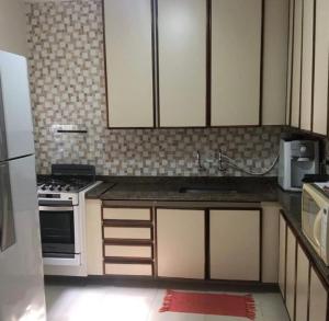 eine Küche mit weißen Schränken und einem Herd mit Backofen in der Unterkunft Hospedaria Litoral in Caraguatatuba