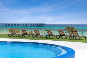 una piscina con sedie e l'oceano sullo sfondo di Chateau Beachfront Hotel, a By the Sea Resort a Panama City Beach
