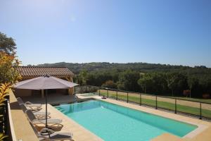 een zwembad met ligstoelen en een parasol bij La Malonie in Sarlat-la-Canéda +7 foto's