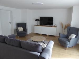 a living room with a couch and two chairs and a tv at Ferienwohnung Gutzeit in Stadtilm