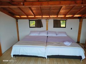 a large bed in a room with two windows at San Luis Cabaña in Curití