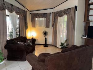 a living room with two brown couches and windows at Villa tico House in Cariari