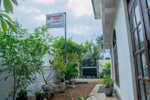 a sign in front of a building with plants at Sunshine Hotel in Hikkaduwa