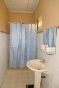 a bathroom with a sink and a blue shower curtain at Sunshine Hotel in Hikkaduwa